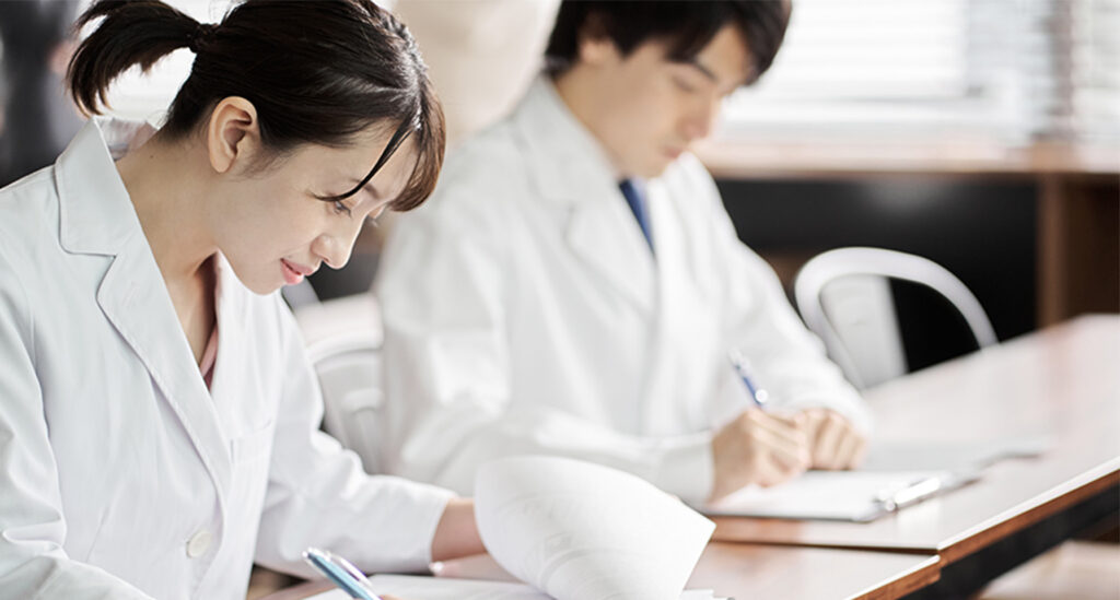 机に向かう2名の白衣を着た男女
