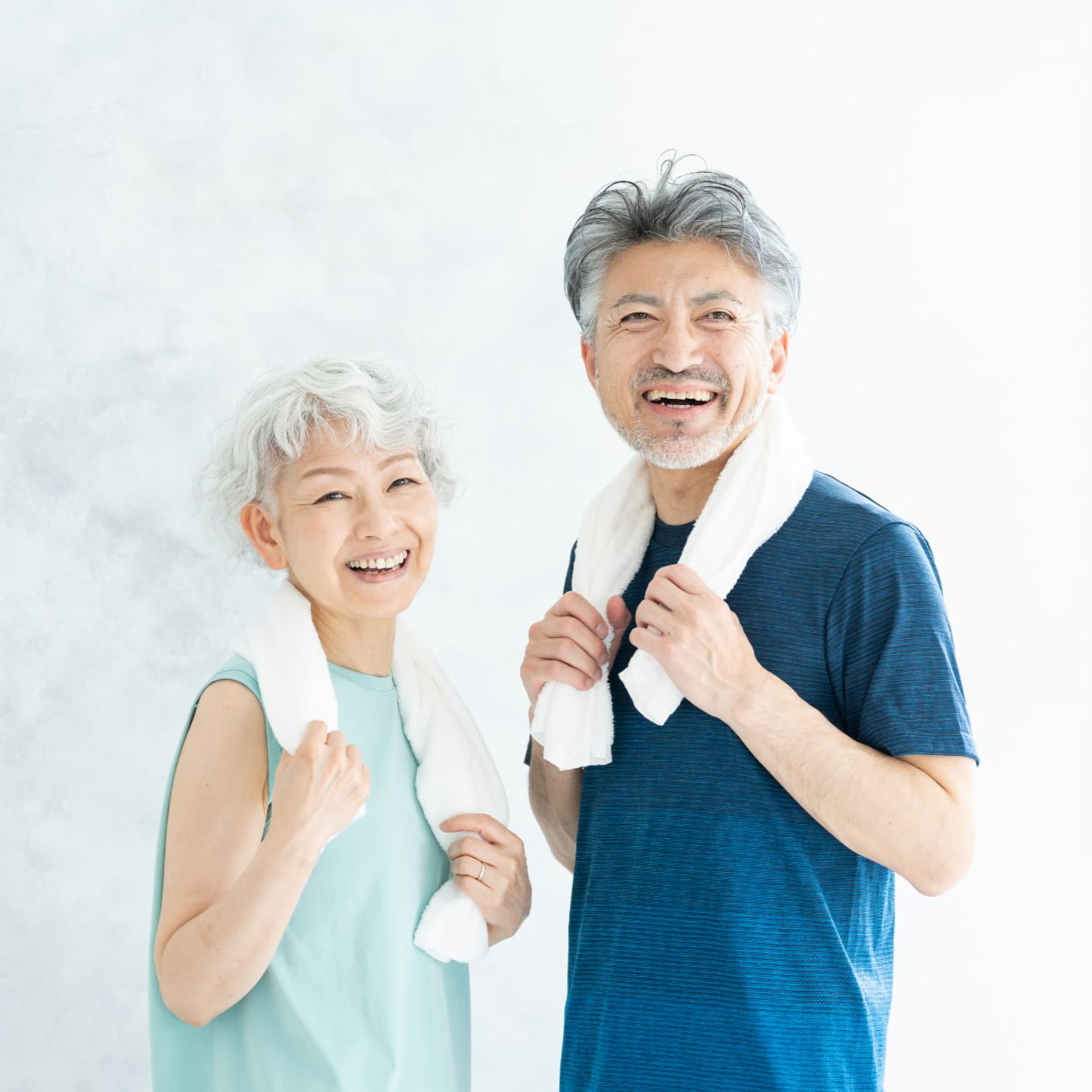 首からタオルをかけて爽やかに笑うシニア男女