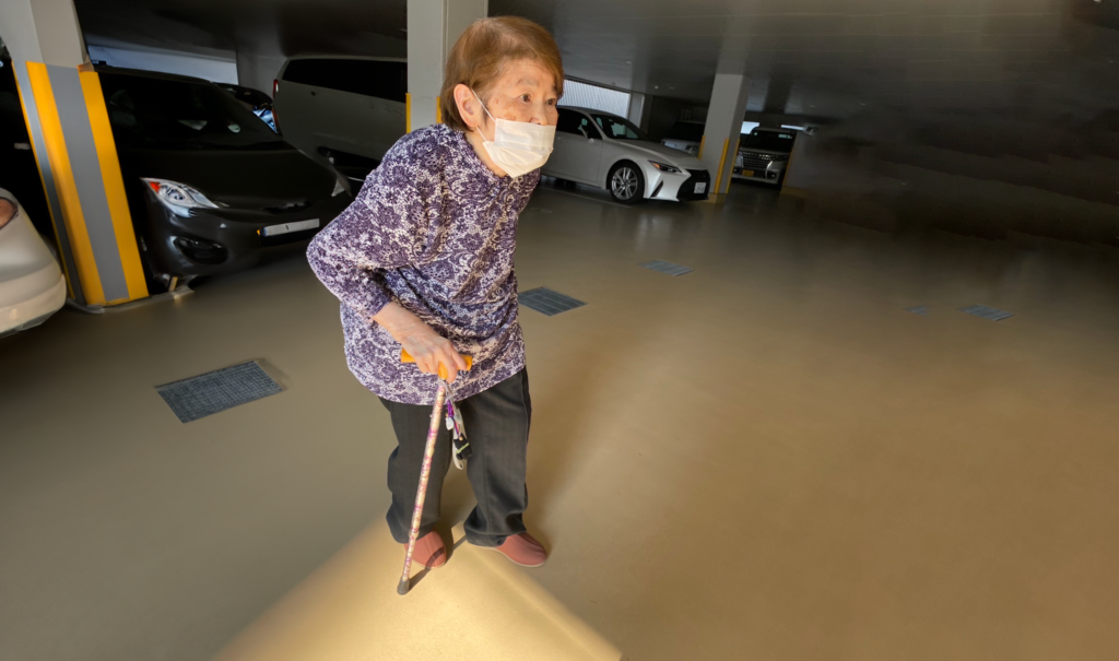 森下フジ子さんが杖をもって歩いている写真